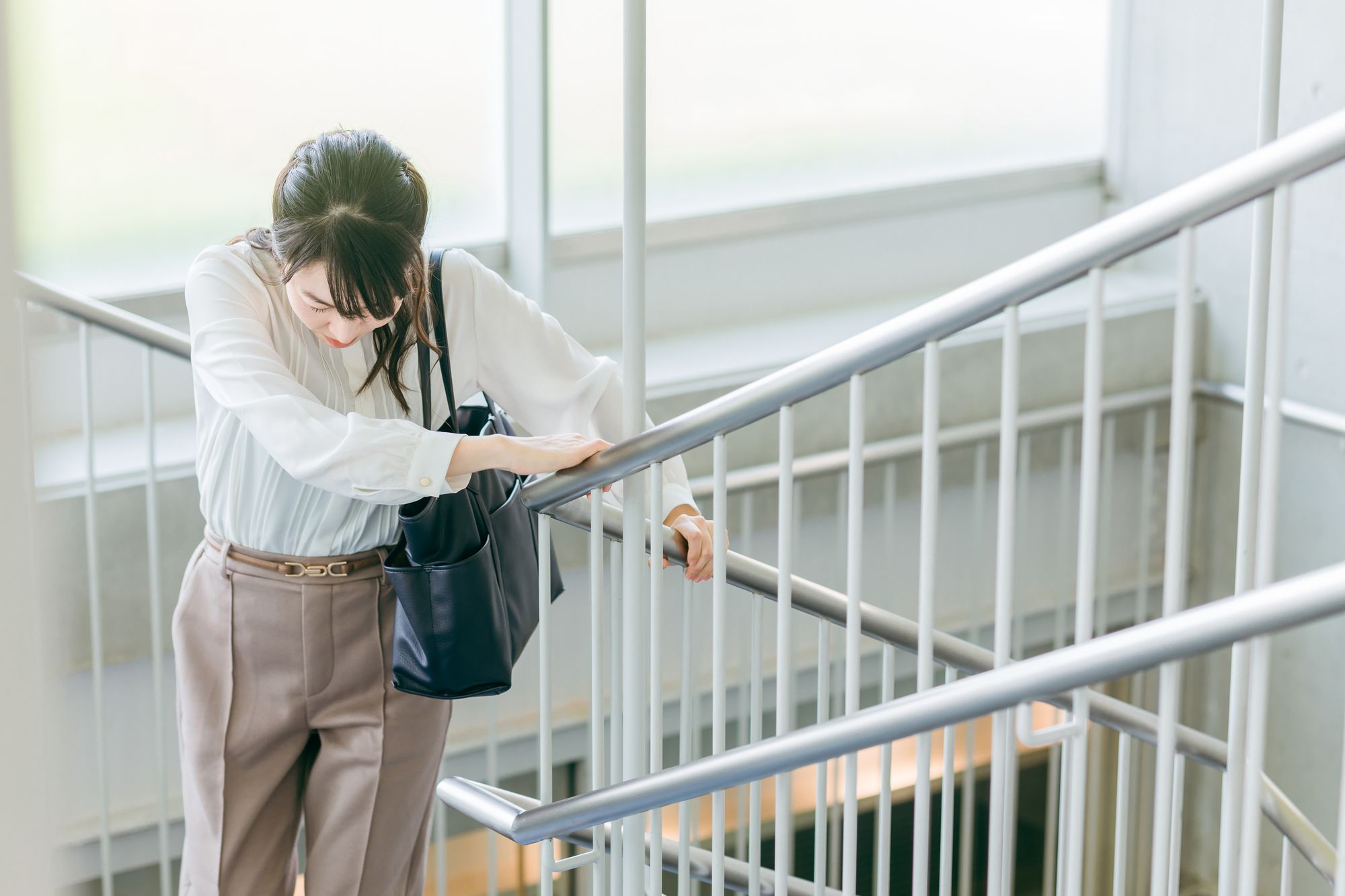 階段を登って息切れをする女性