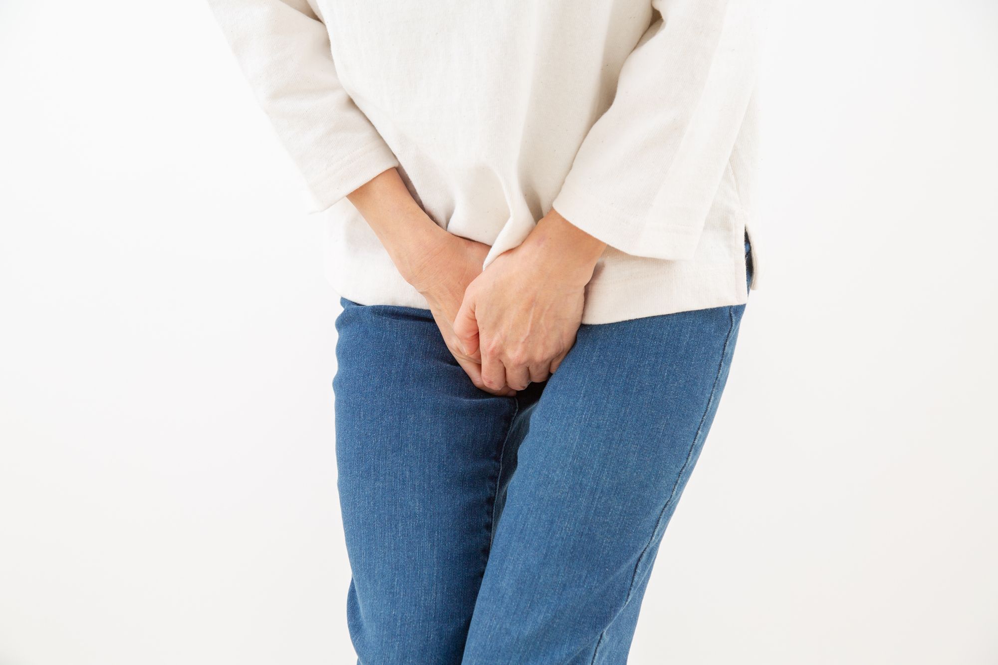 股間を押さえて尿を我慢する女性