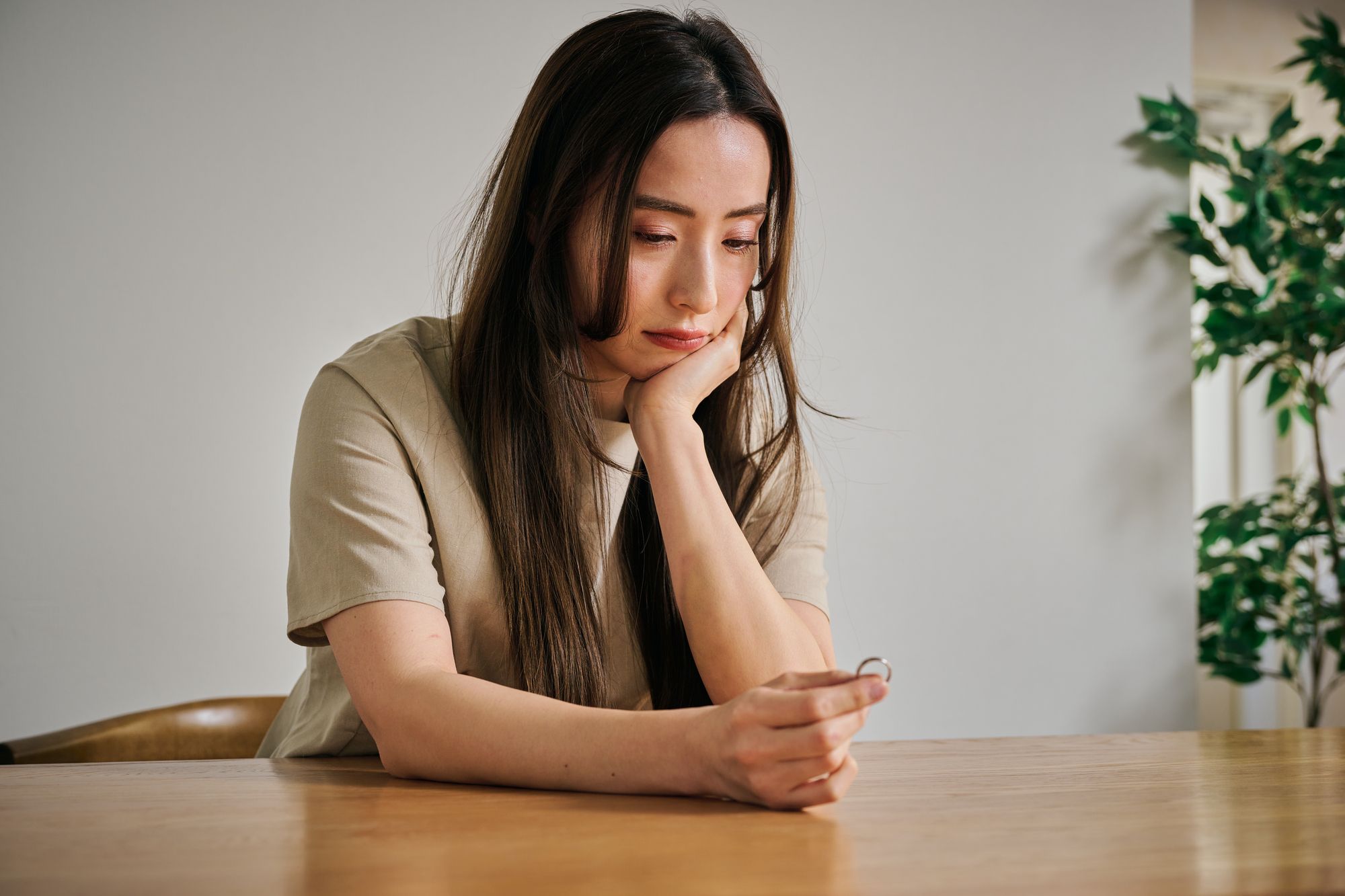 テーブルで指輪を見つめて悩む女性