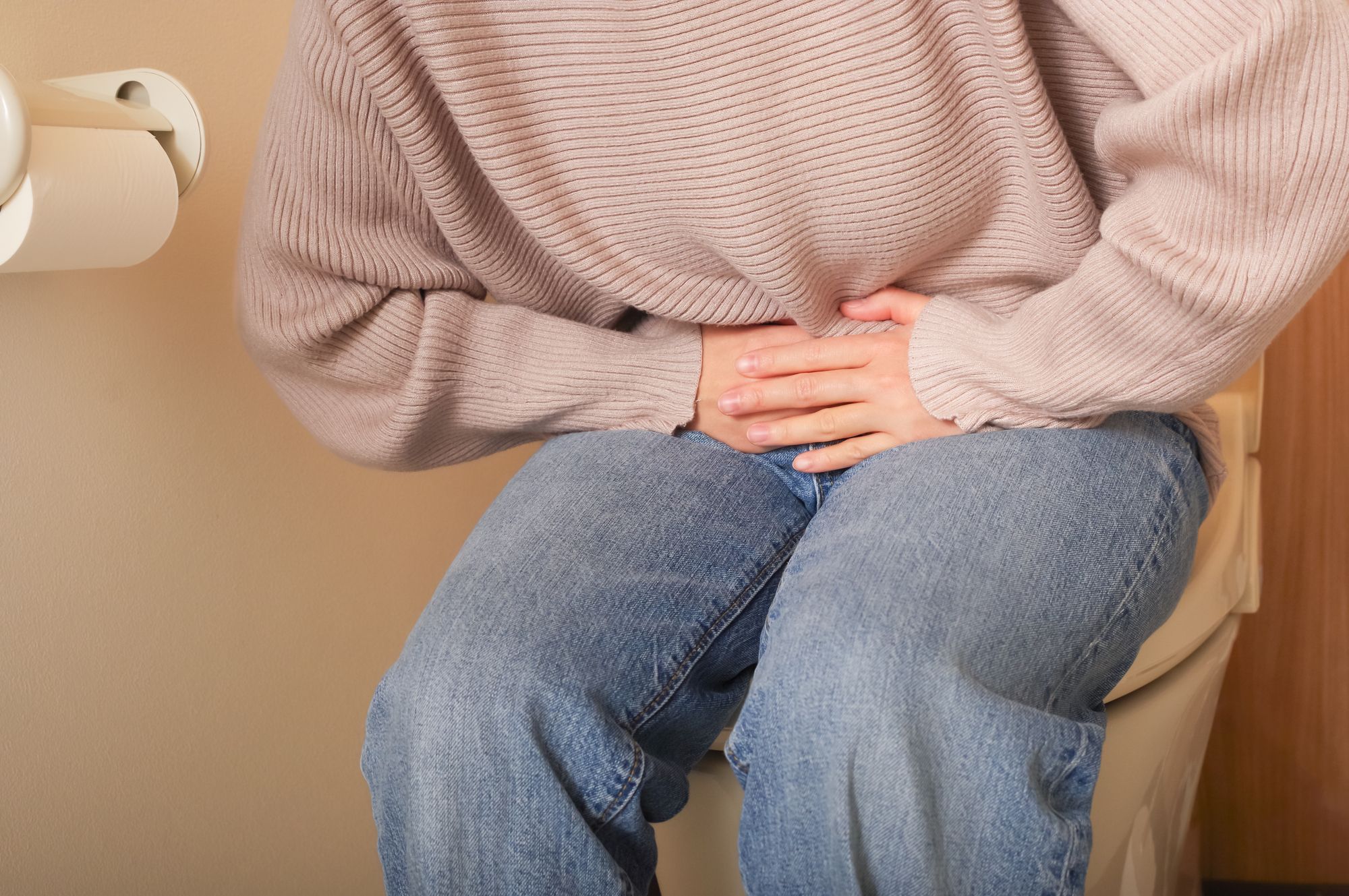 トイレで腹痛のためお腹を抱える女性
