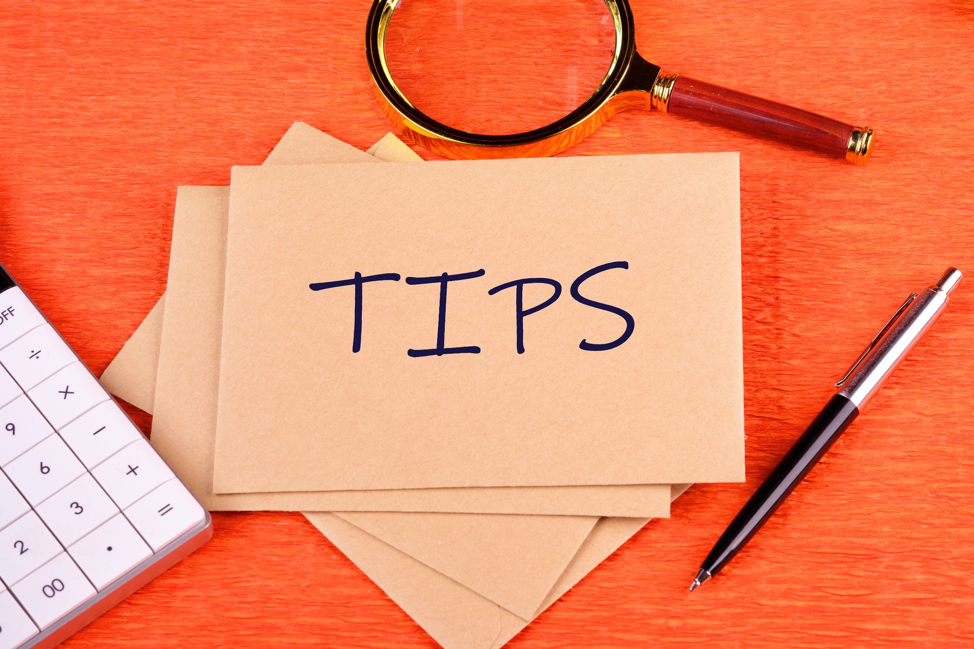「TIPS」と書かれたメモと電卓、ペンが置かれたデスク