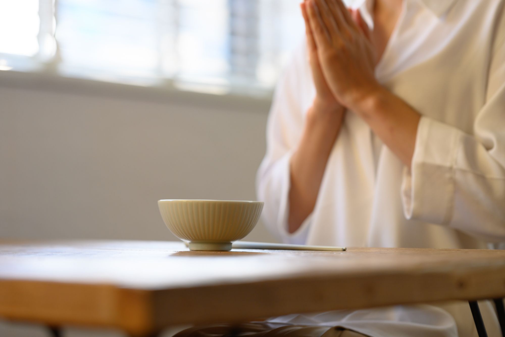 お茶碗を前に、いただきますと手をあわせる女性