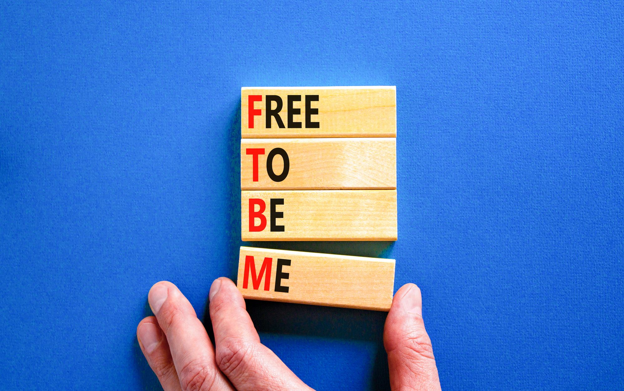 Free To Be Meと書かれた積み木をもつ手