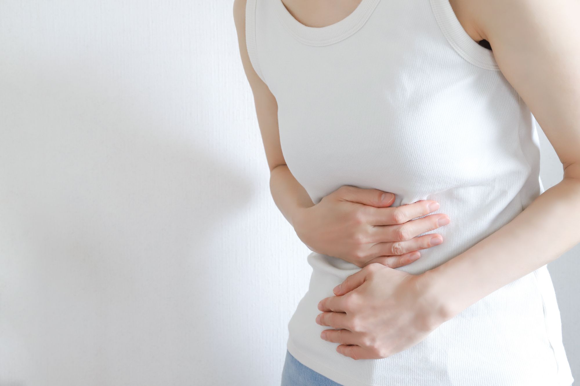 腹痛でお腹に手を当てる女性