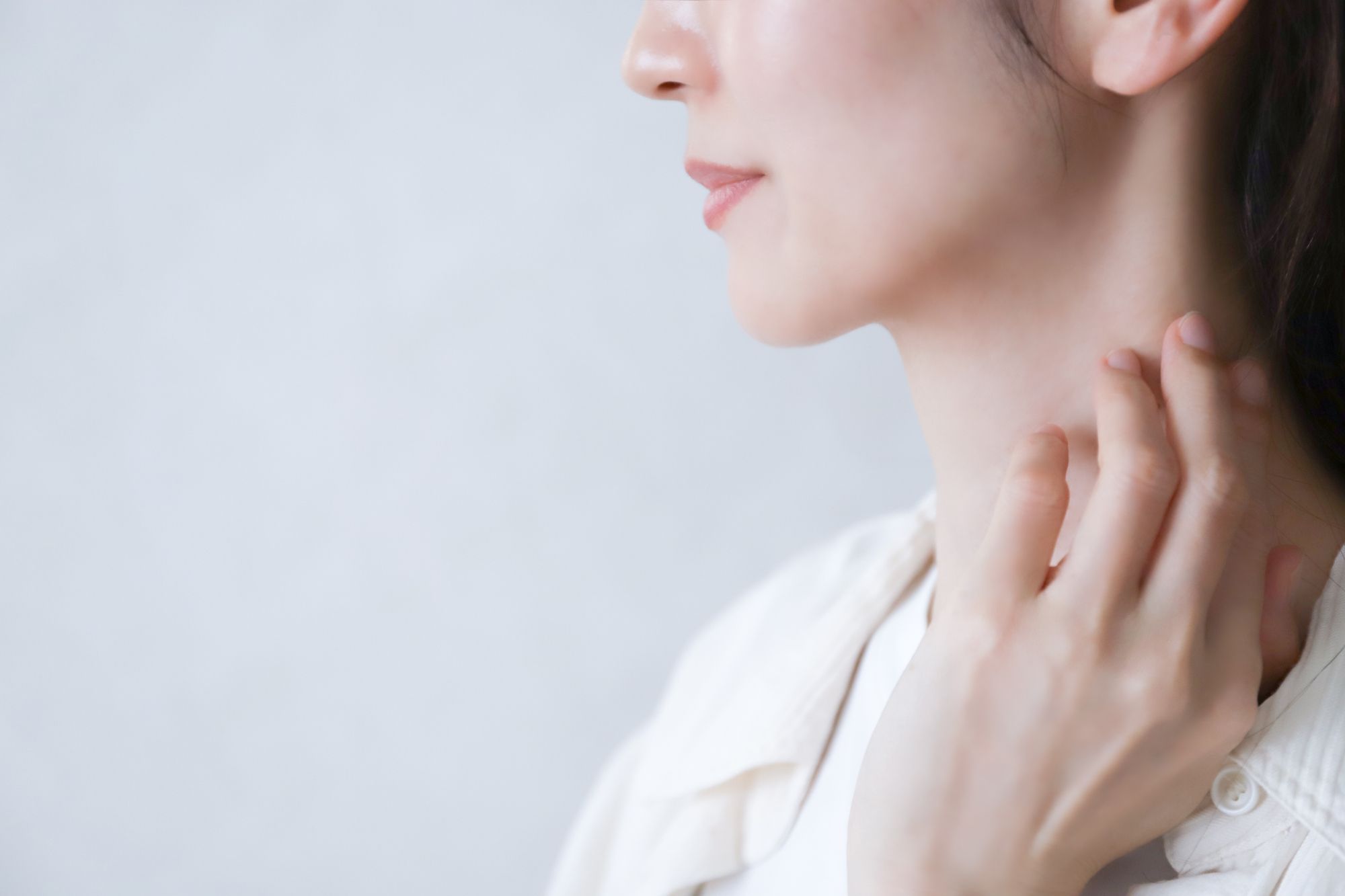 首に軽く指を触れた女性の横顔