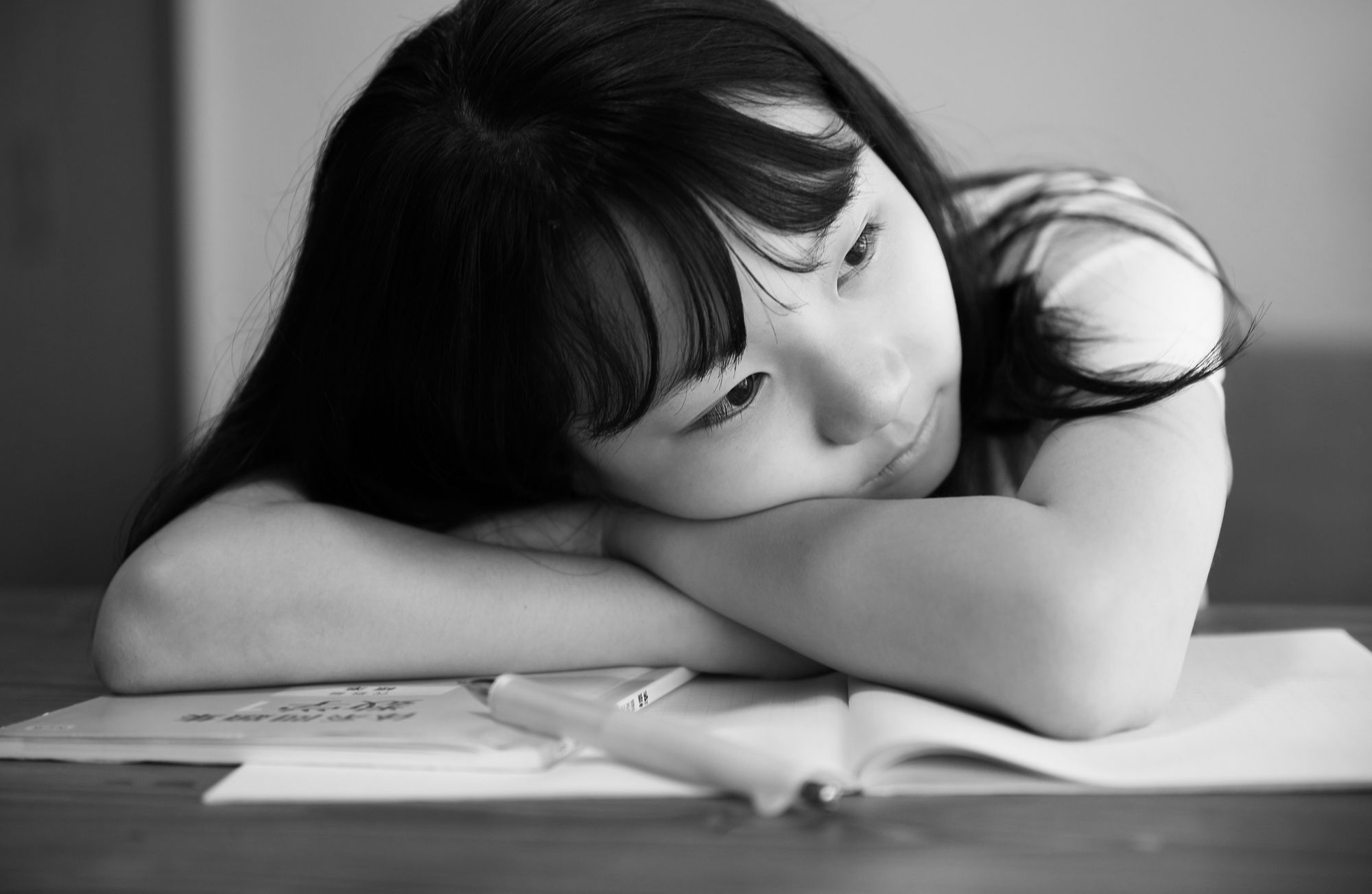 勉強机に伏せて外を眺める女の子
