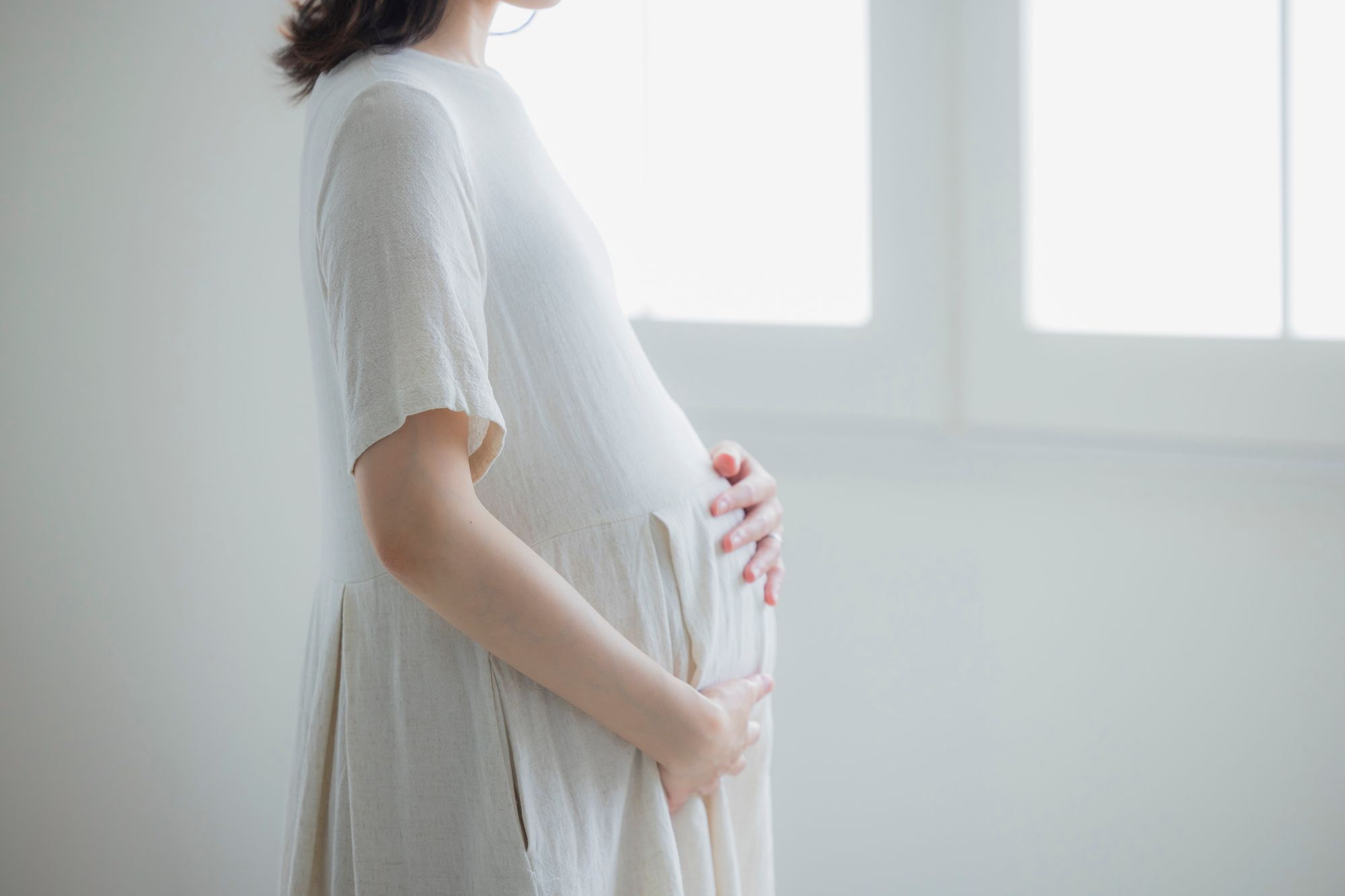 おなかに手をあてるワンピースを着た妊婦さん