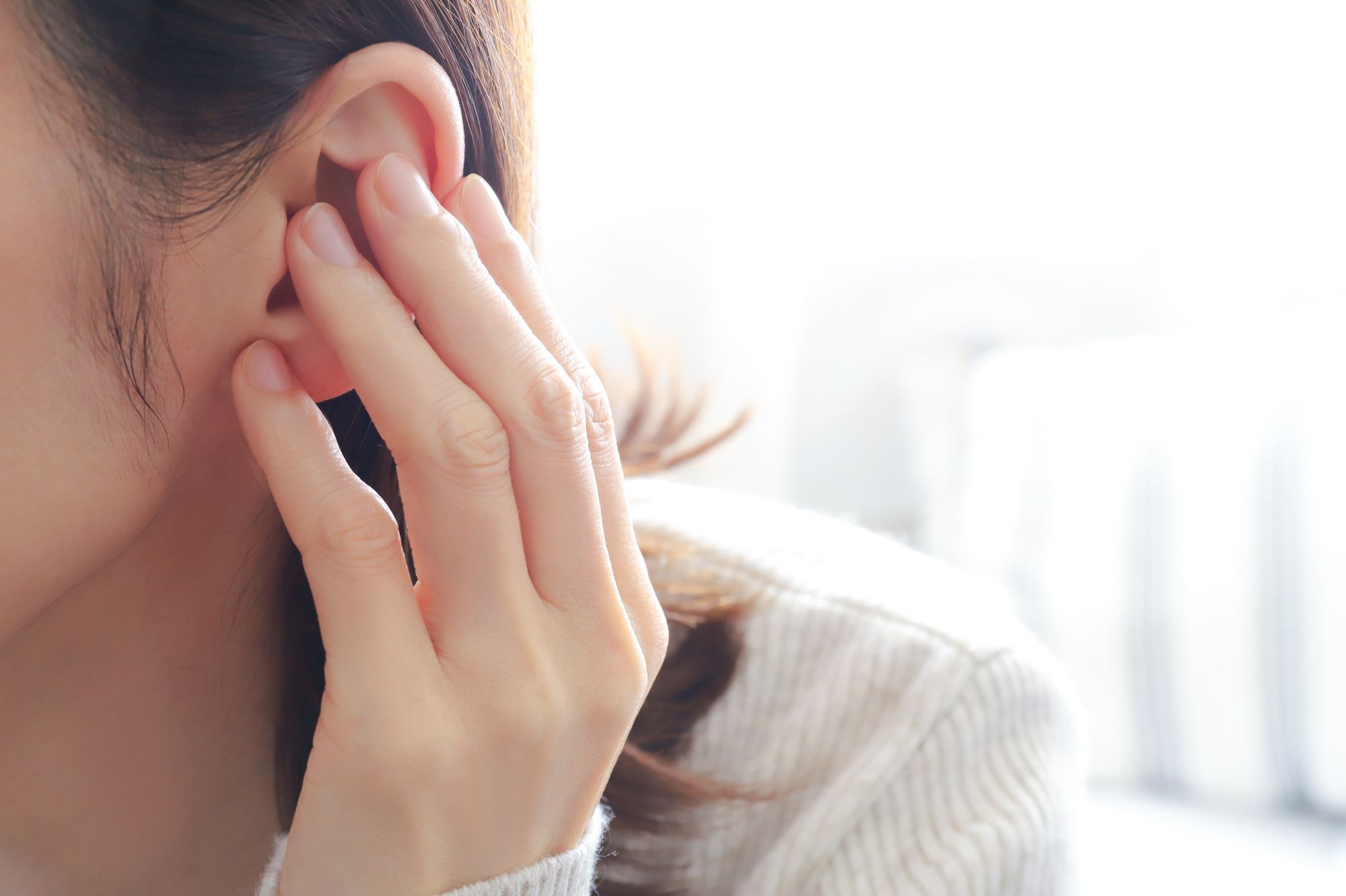 違和感を感じて耳を触る女性
