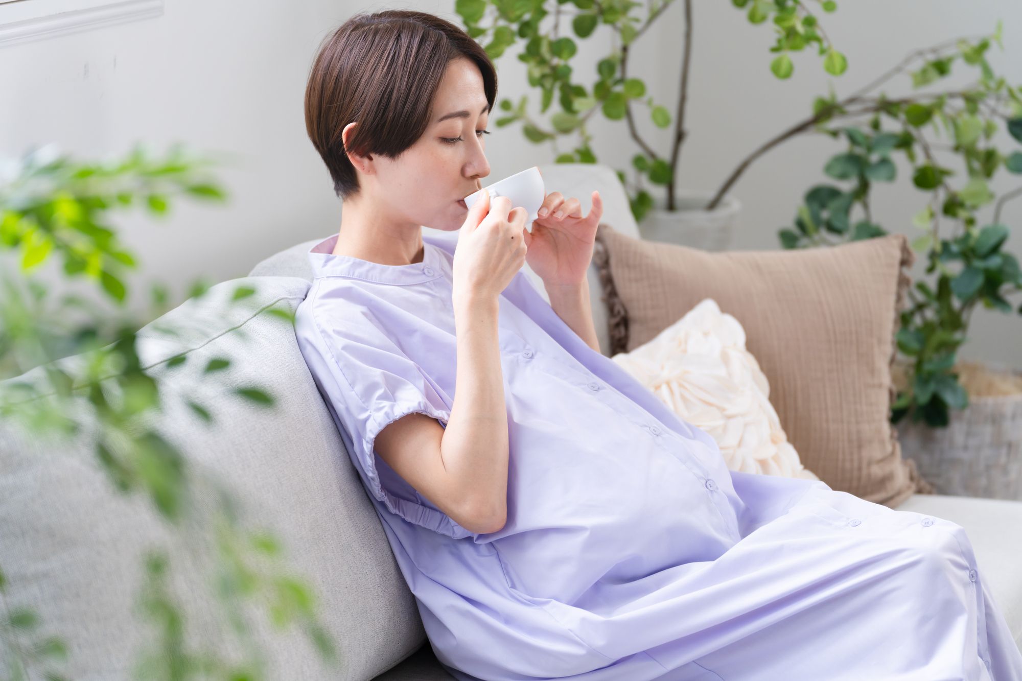 カップに入った飲み物を飲む妊婦さん