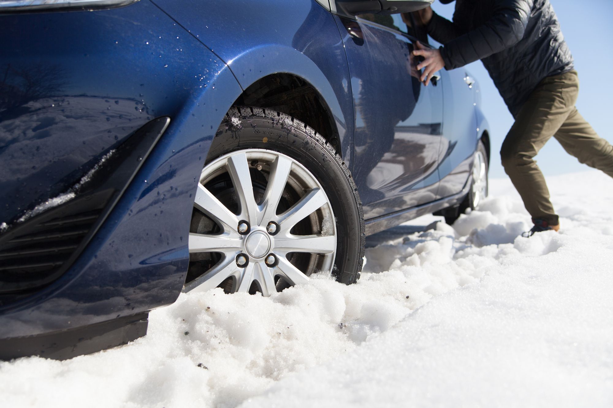 雪道でスタックした車を押す男性