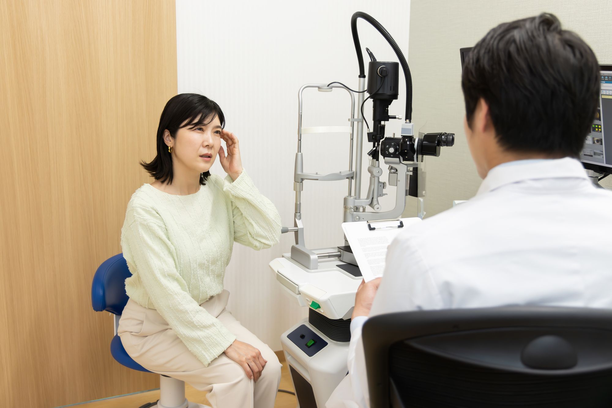 眼科の診察室で医師に相談する女性