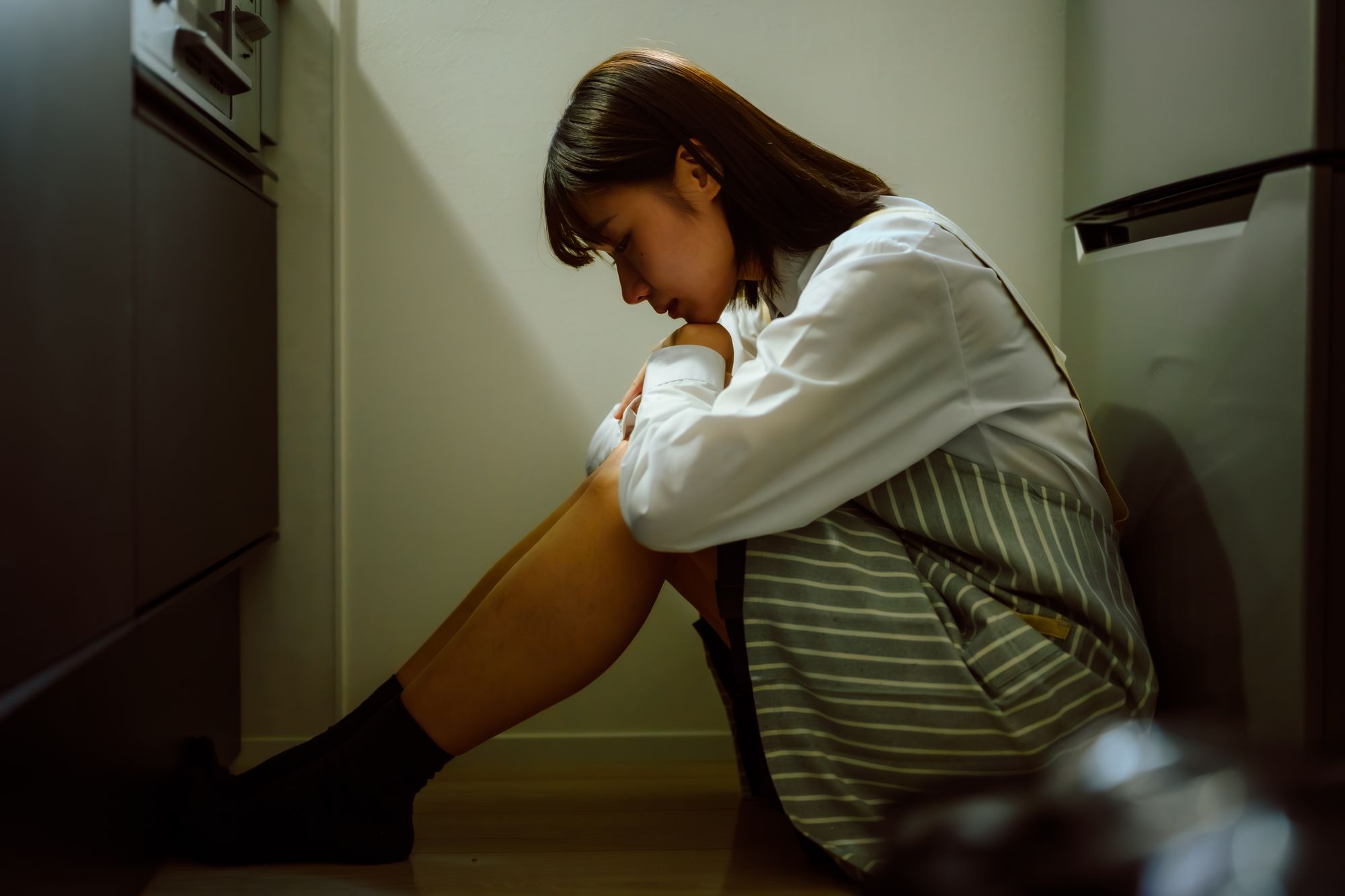 キッチンの暗がりで膝を抱える女子生徒