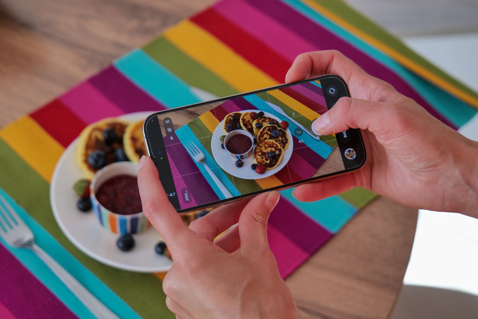 スマートフォンでおやつのパンケーキを撮影する手