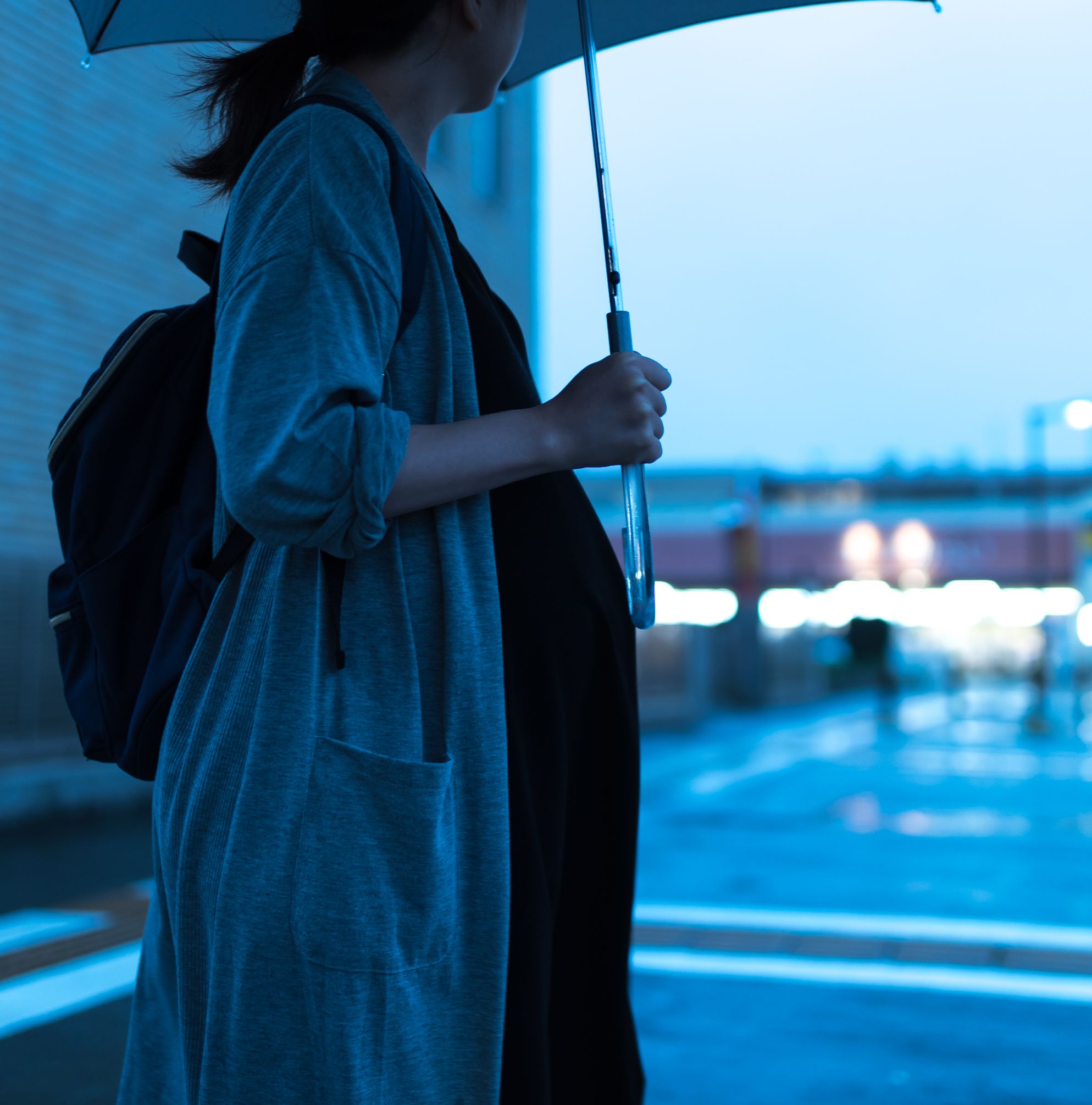 雨傘を刺して道路を渡る妊婦さん