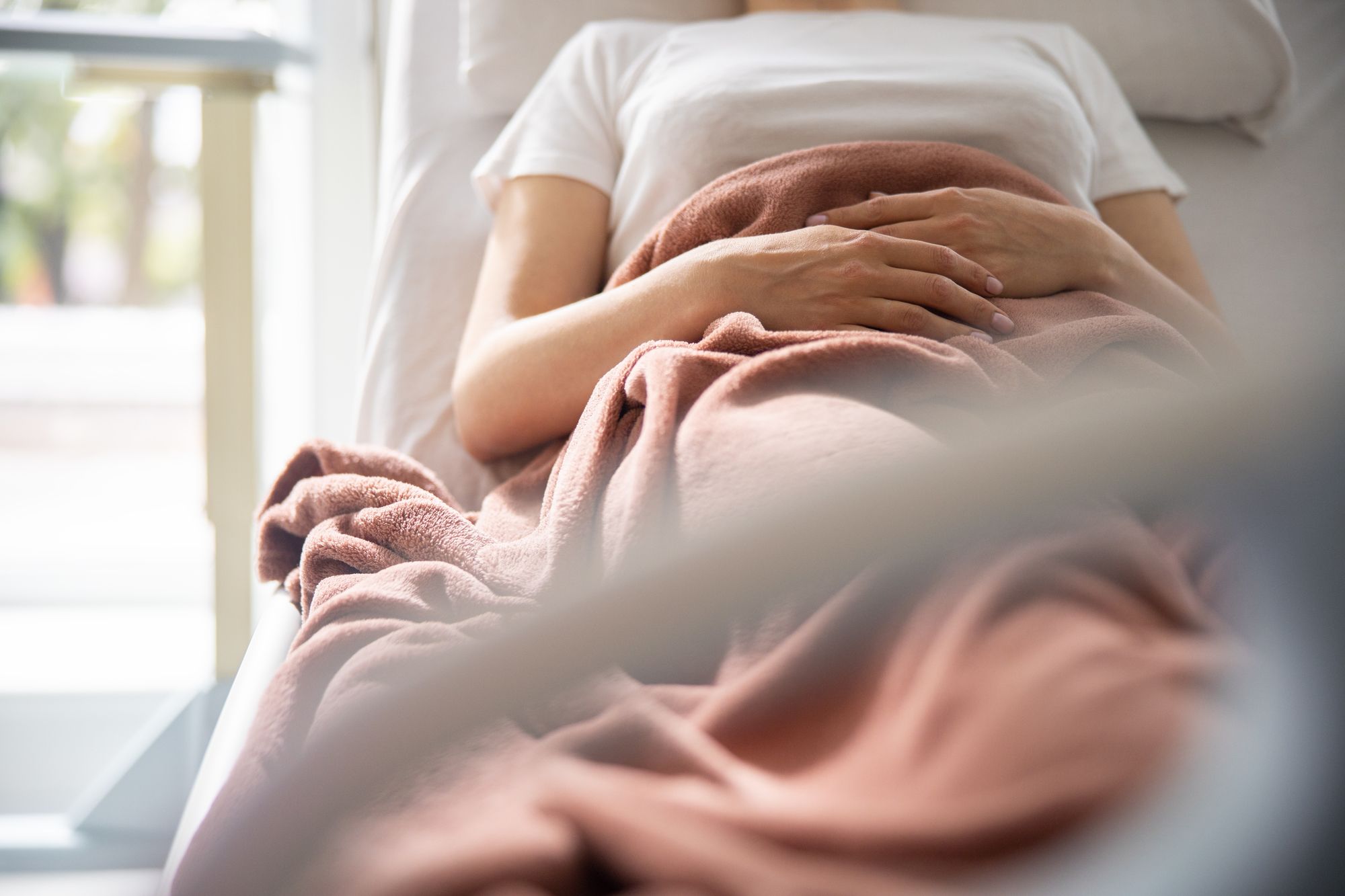 おなかを抱いてベッドに横たわる妊婦さん