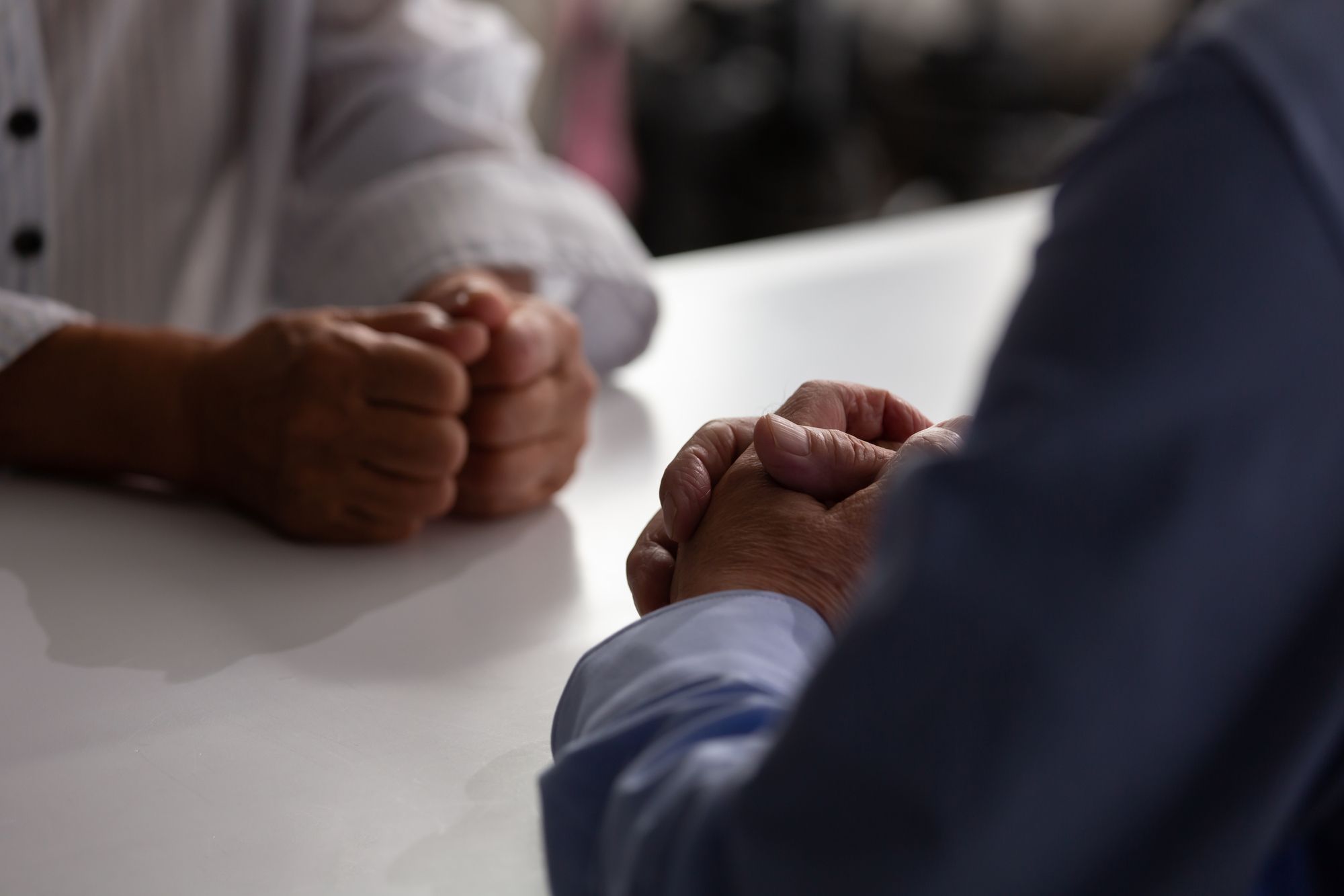 テーブルに向き合って話す夫婦同士の手