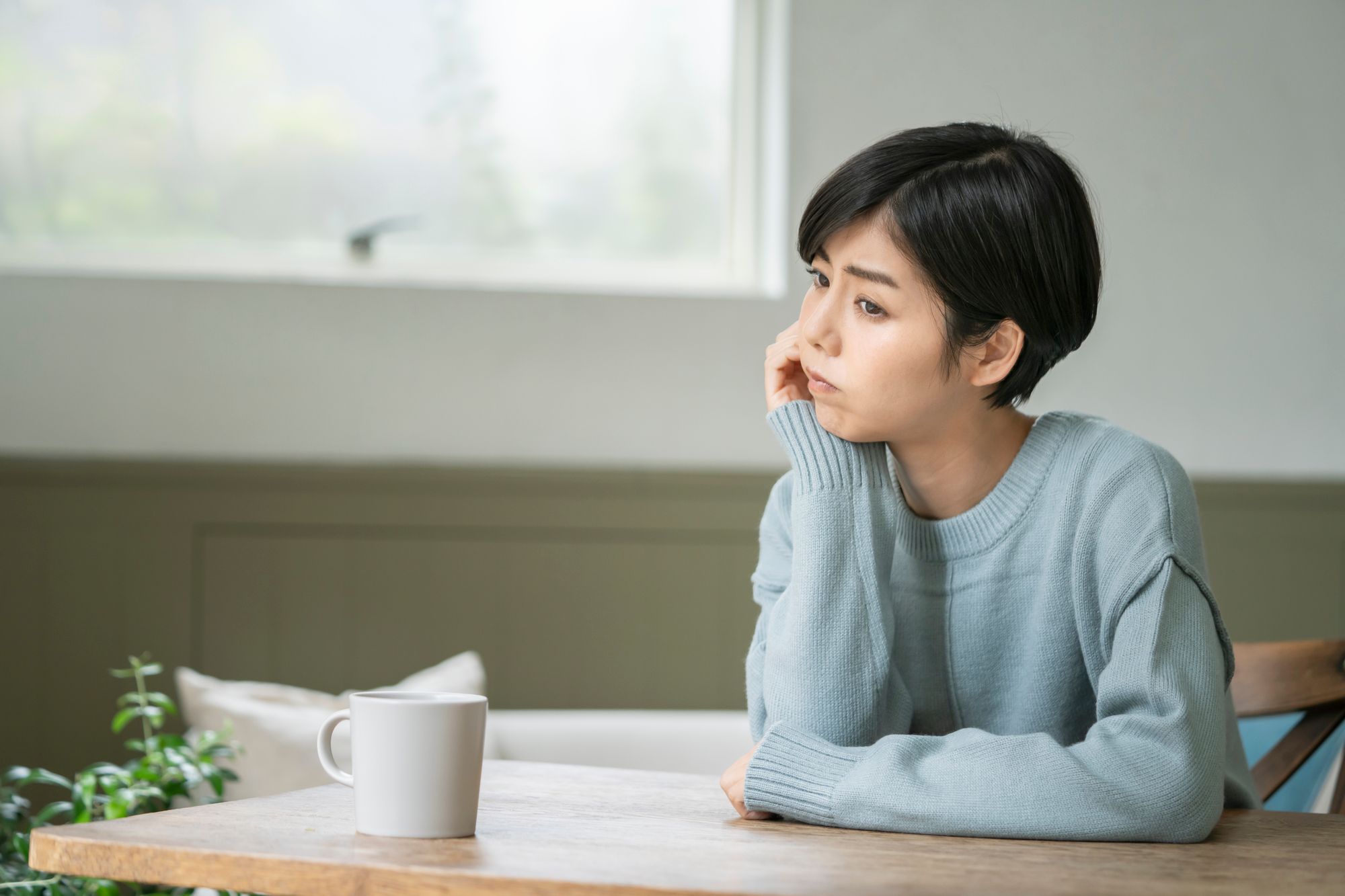頬杖をついて悩む女性