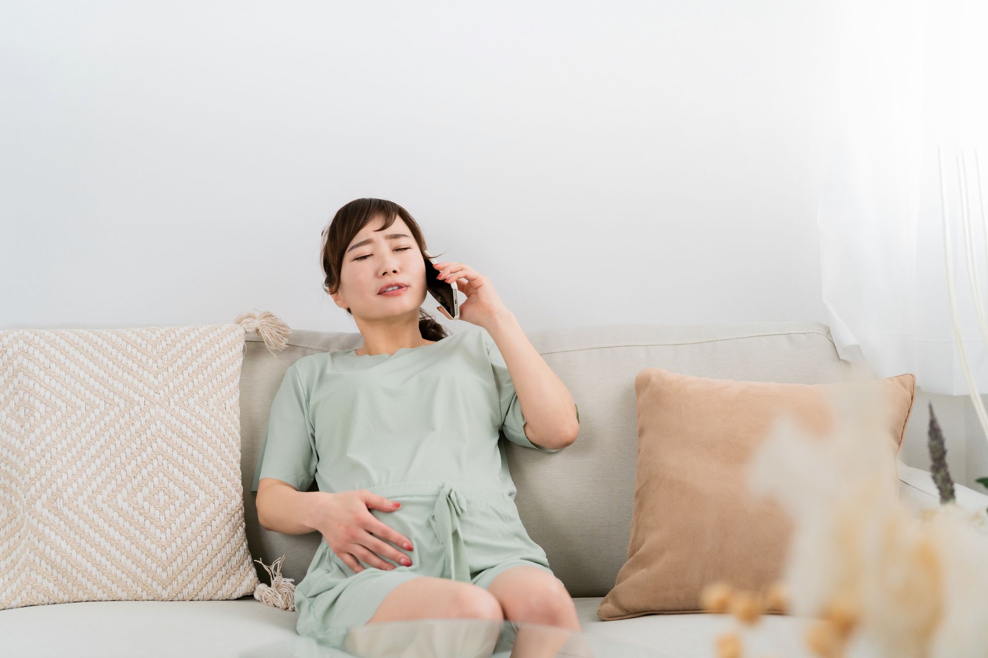 お腹に痛みを訴えて電話する妊婦さん