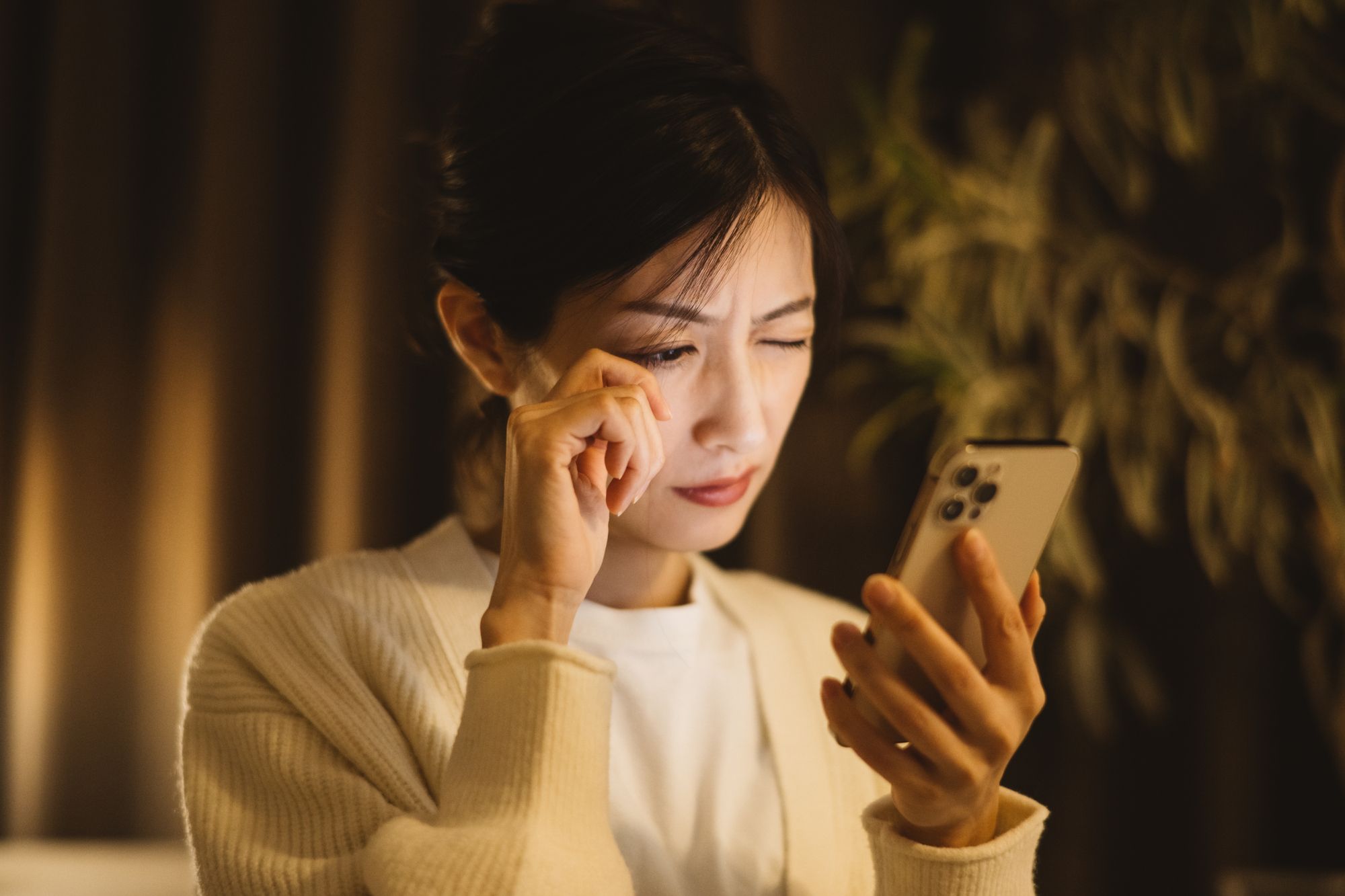 スマホを見て目の疲れを感じる女性