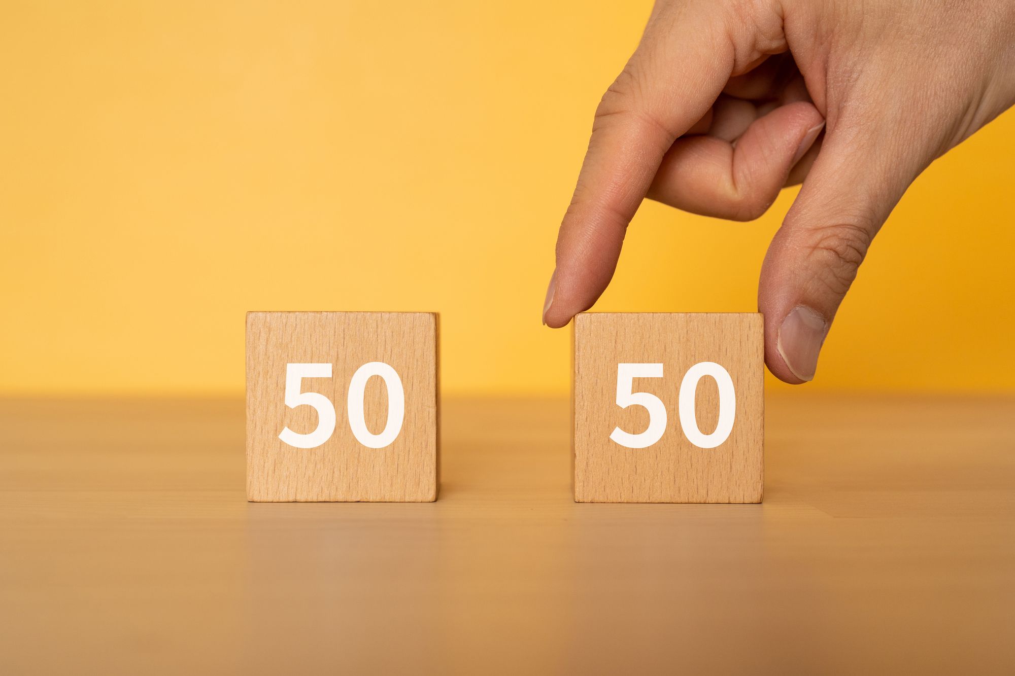 50:50の積み木をつまむ女性の手