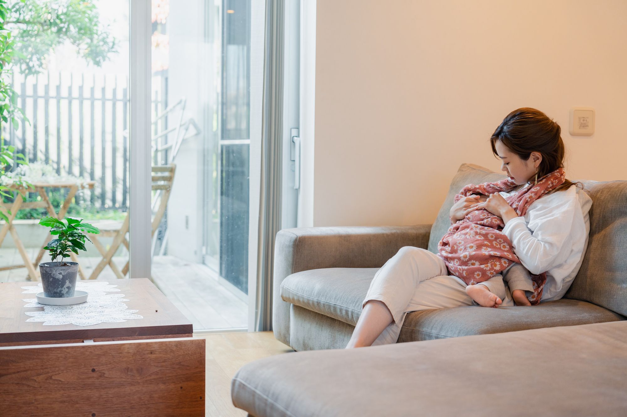 ソファーで授乳する若い女性
